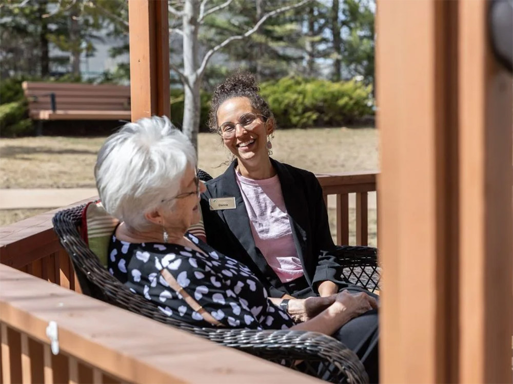 resident talking to staff at outdoor bench